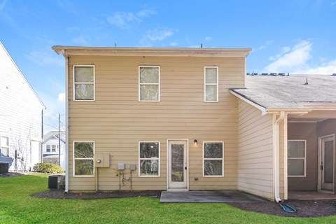 A beige house with a grey roof and a white fence.