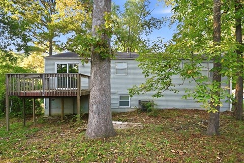 A house with a deck and a tree in front.