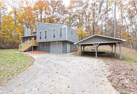 a gray house with a gravel driveway and a gray shed