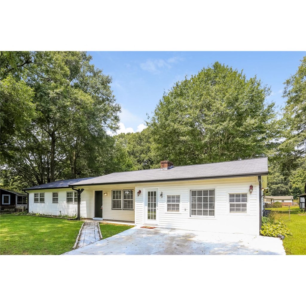 a small white house with a yard and trees