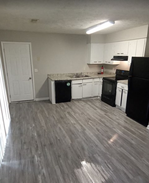 a kitchen with white cabinets and a wooden floor