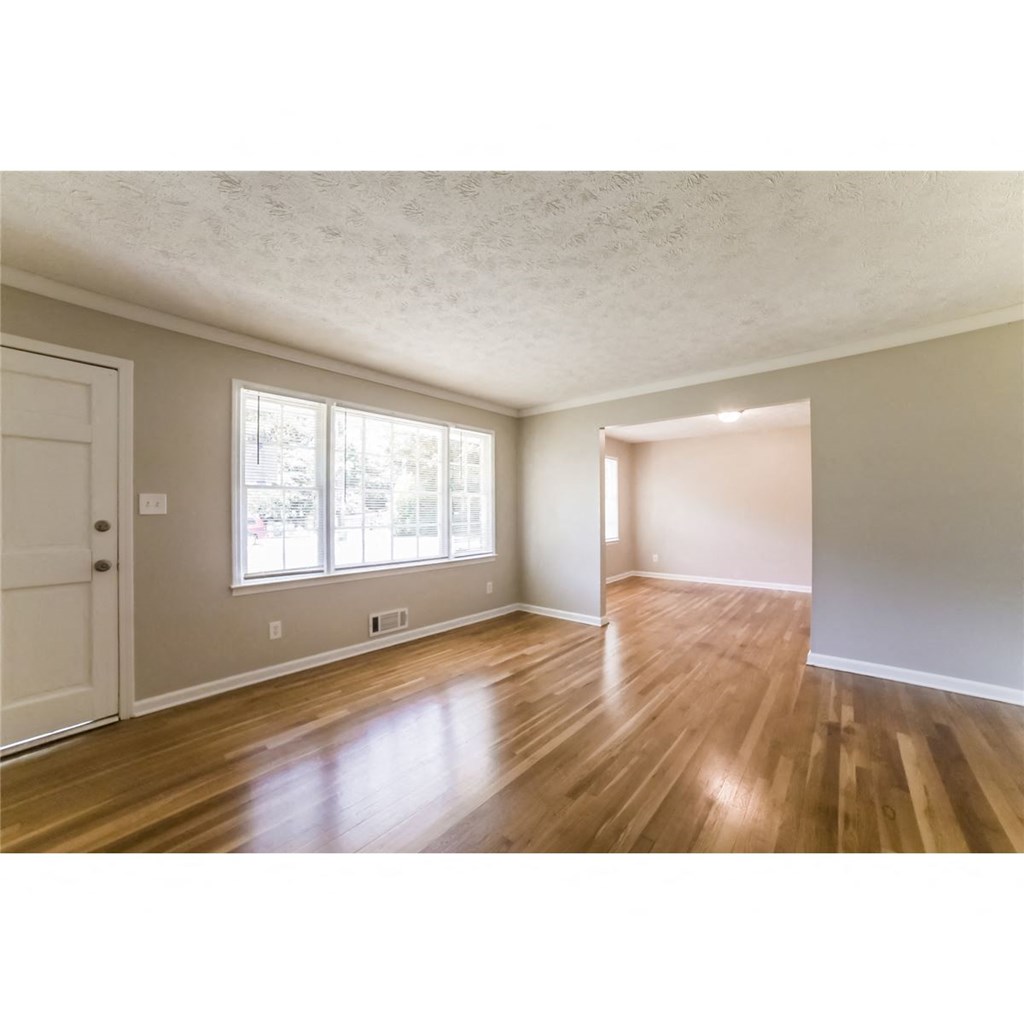 an empty living room with wood floors and a window