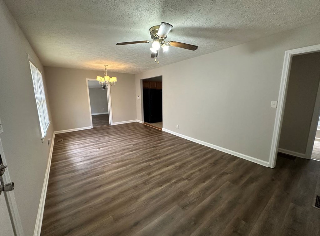 an empty living room with wood floors and a ceiling fan