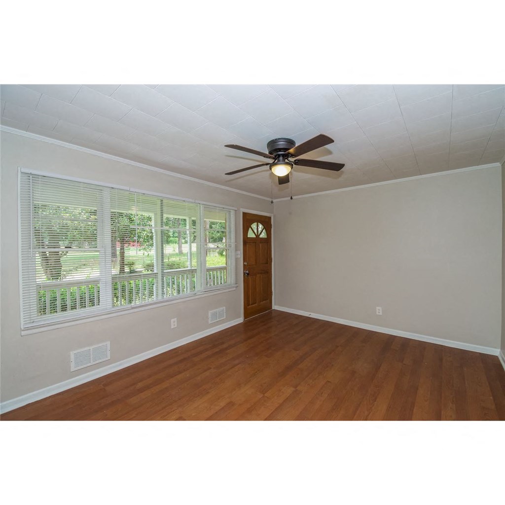 an empty living room with a ceiling fan and a window