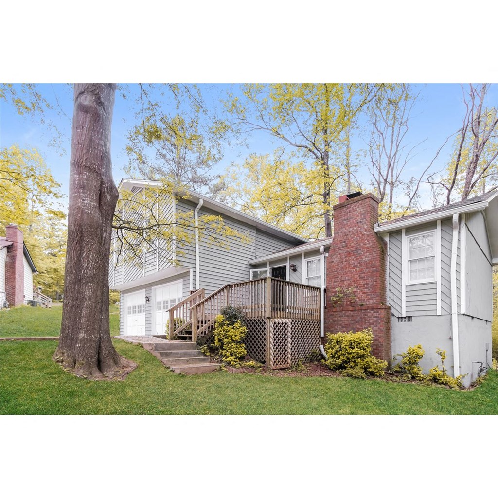 a view of the front of a house with a deck and a tree