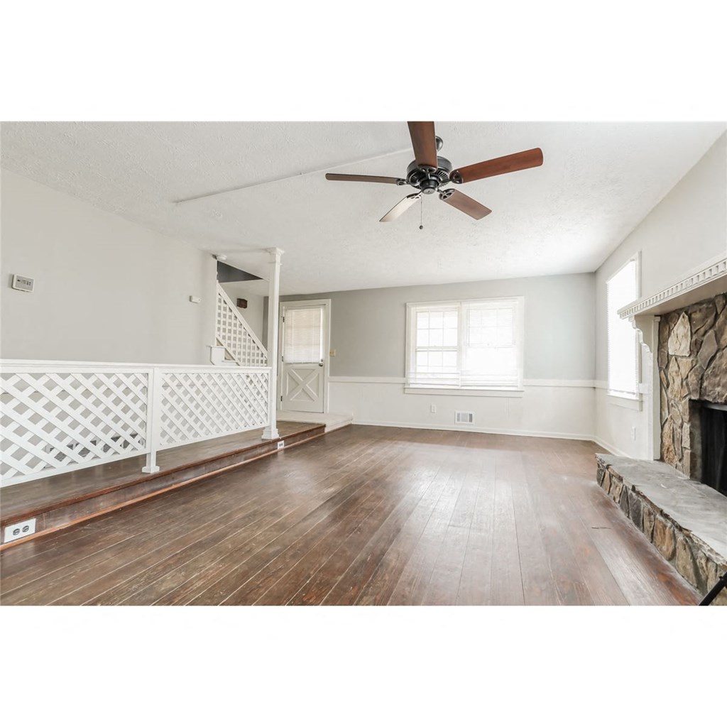 an empty living room with a ceiling fan and a fireplace