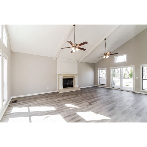 an open living room with a fireplace and two ceiling fans