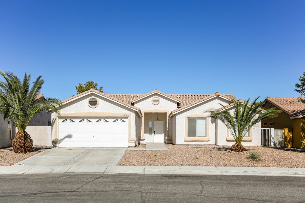 A house with a white garage door and a palm tree in front.