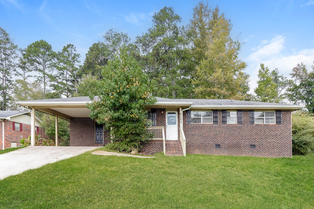 A house with a green lawn and trees in the background.