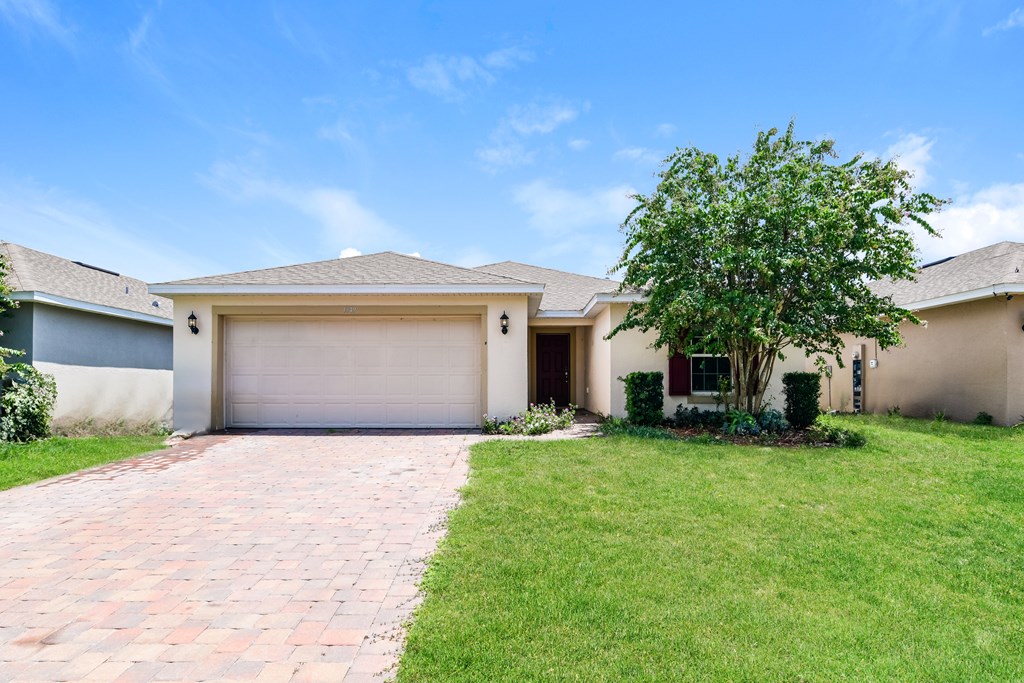 A house with a garage and a tree in front.