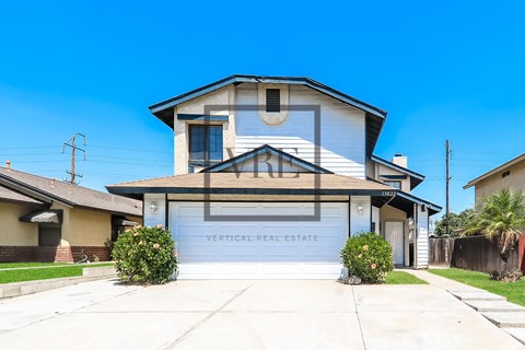 A two-story house with a garage and a sign that says "Vertical Real Estate".