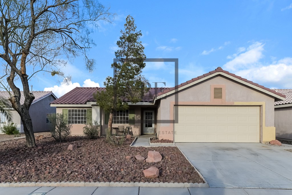 A house with a garage and a tree in front.