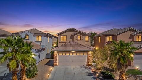 A row of houses with garages and palm trees in front.