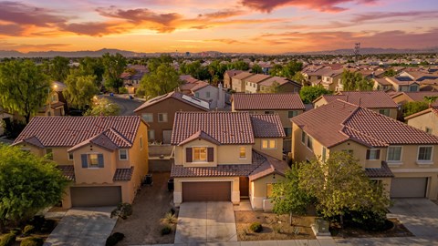 A large house with a red tile roof is surrounded by other houses.