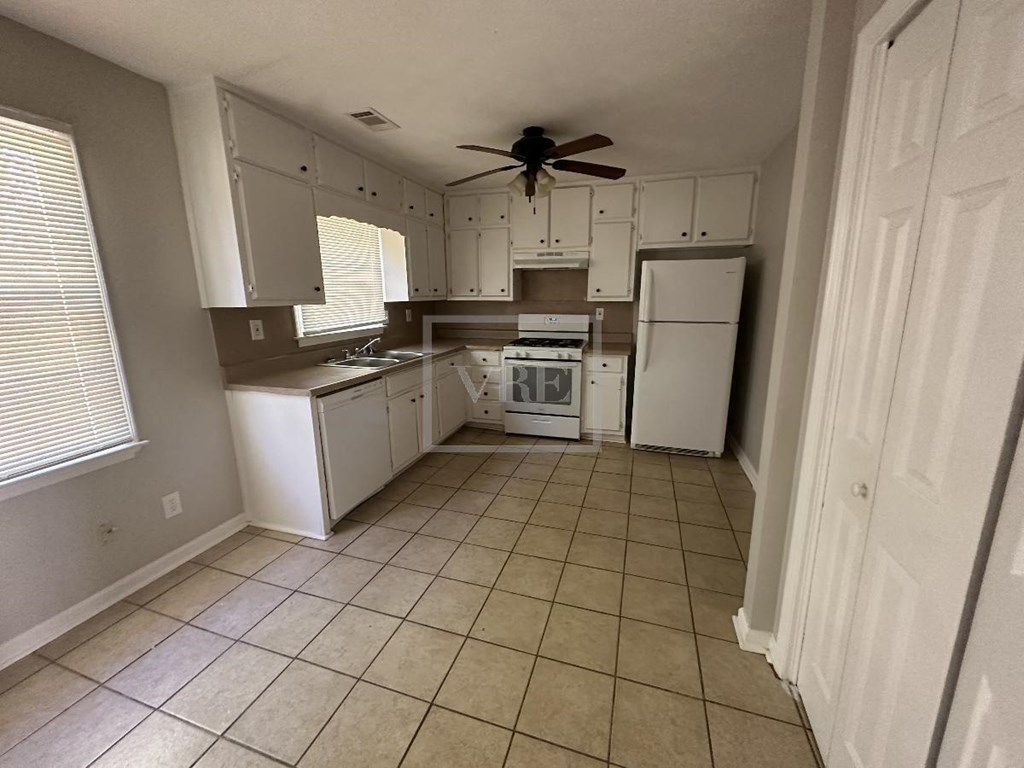 a kitchen with white appliances and a ceiling fan