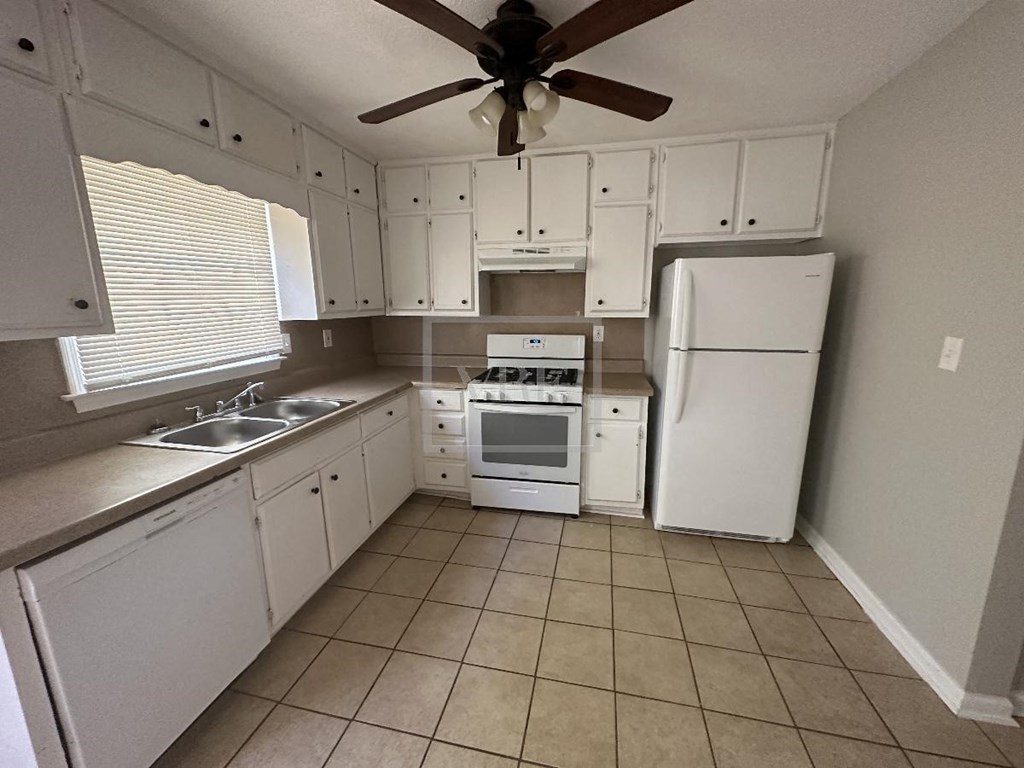 a kitchen with white appliances and a ceiling fan