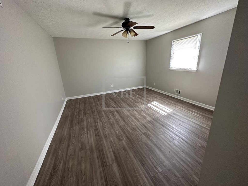 an empty room with hardwood floors and a ceiling fan