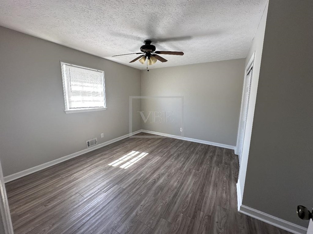 an empty living room with wood floors and a ceiling fan