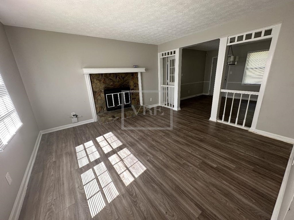an empty living room with a fireplace and wooden floors