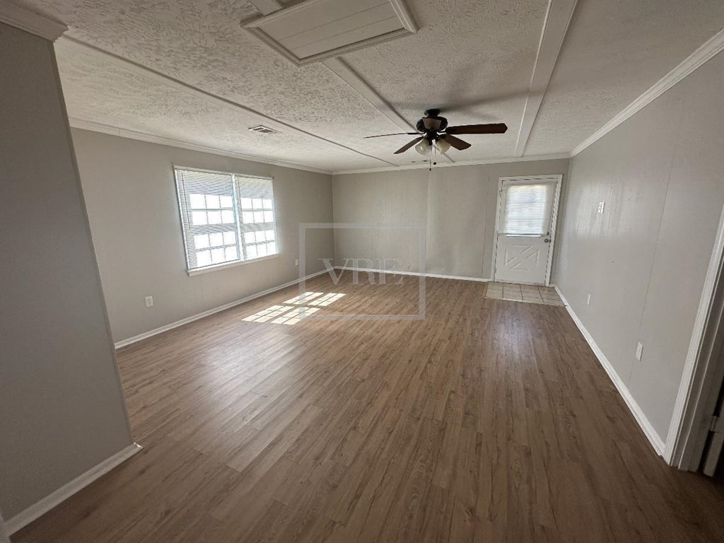 an empty living room with a ceiling fan and wood floors