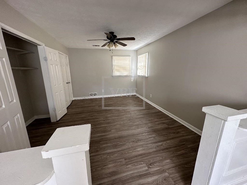 a empty living room with a ceiling fan and a closet
