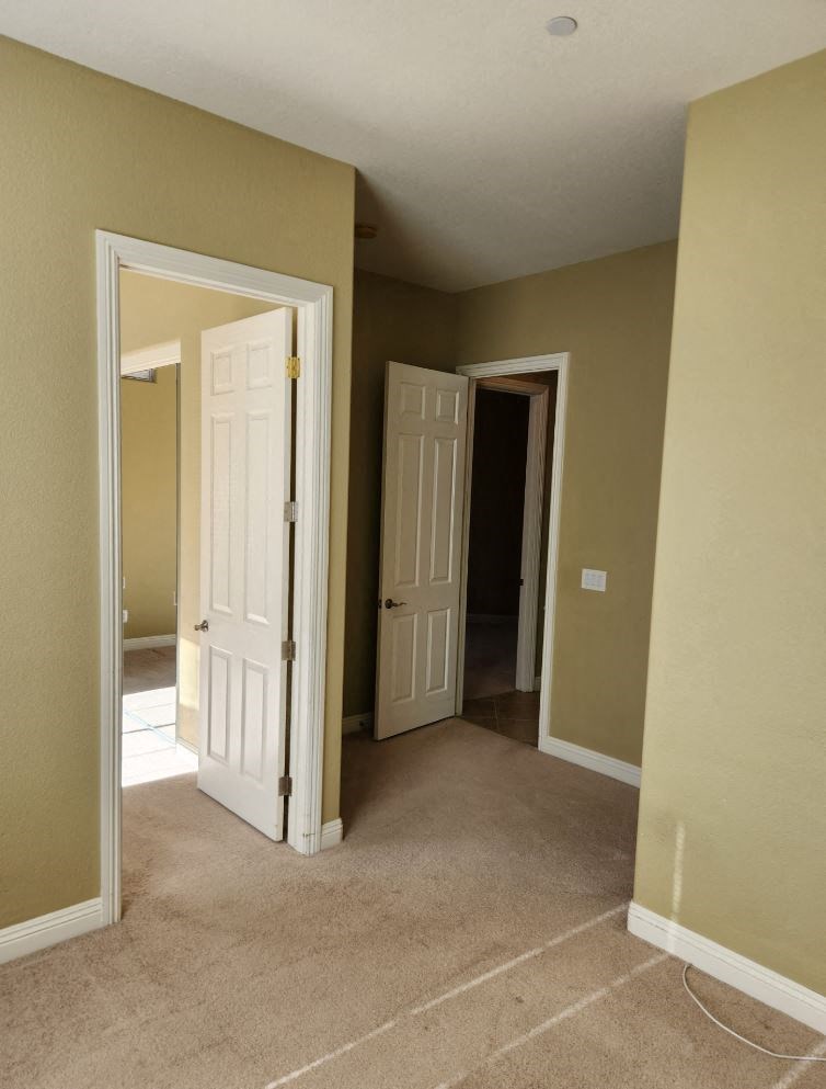an empty hallway with two doors and a door to a bedroom