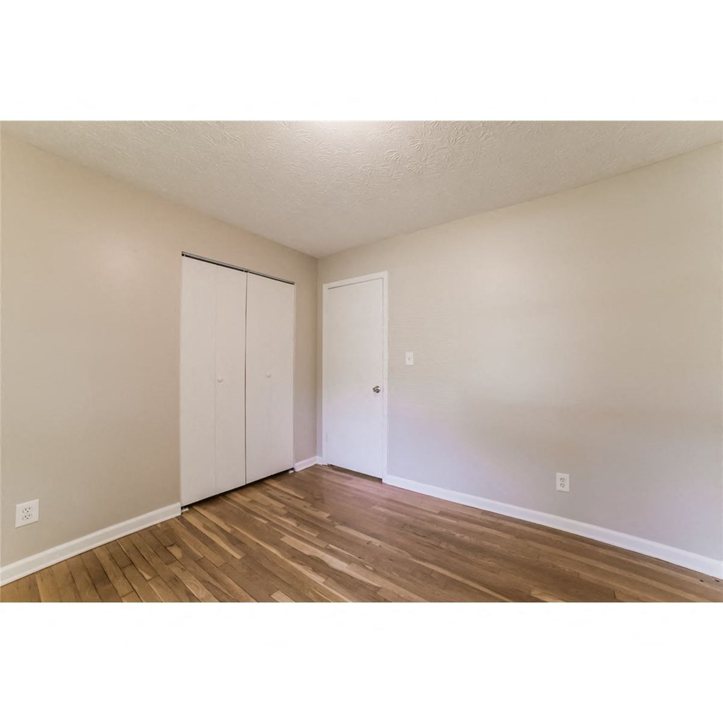 an empty living room with wood floors and a closet