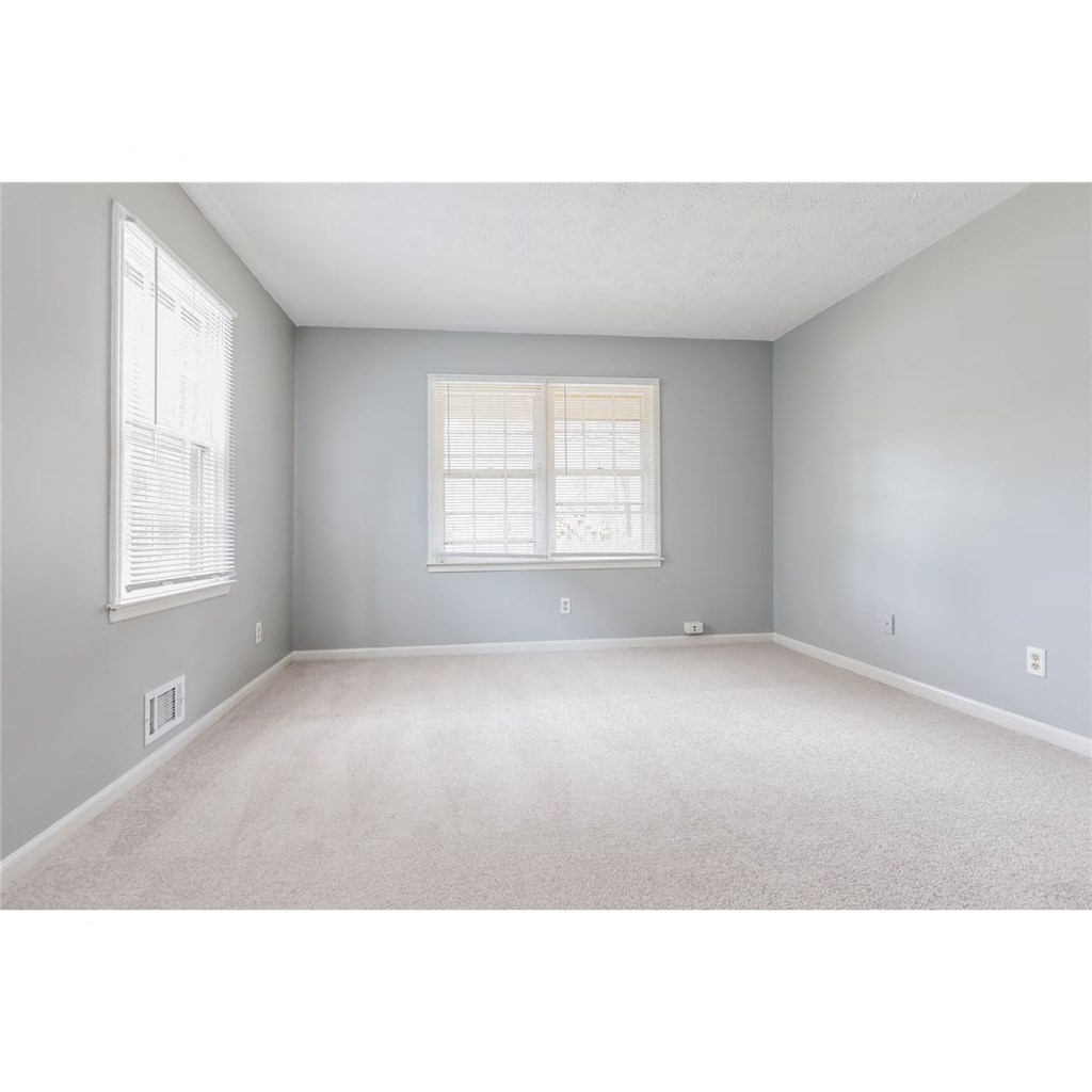 an empty living room with a window and carpet