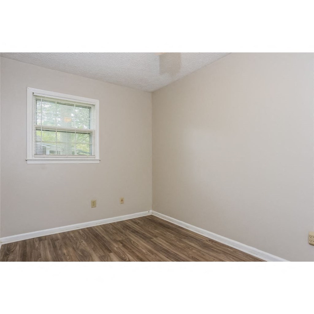 a corner of a room with a window and wooden floors
