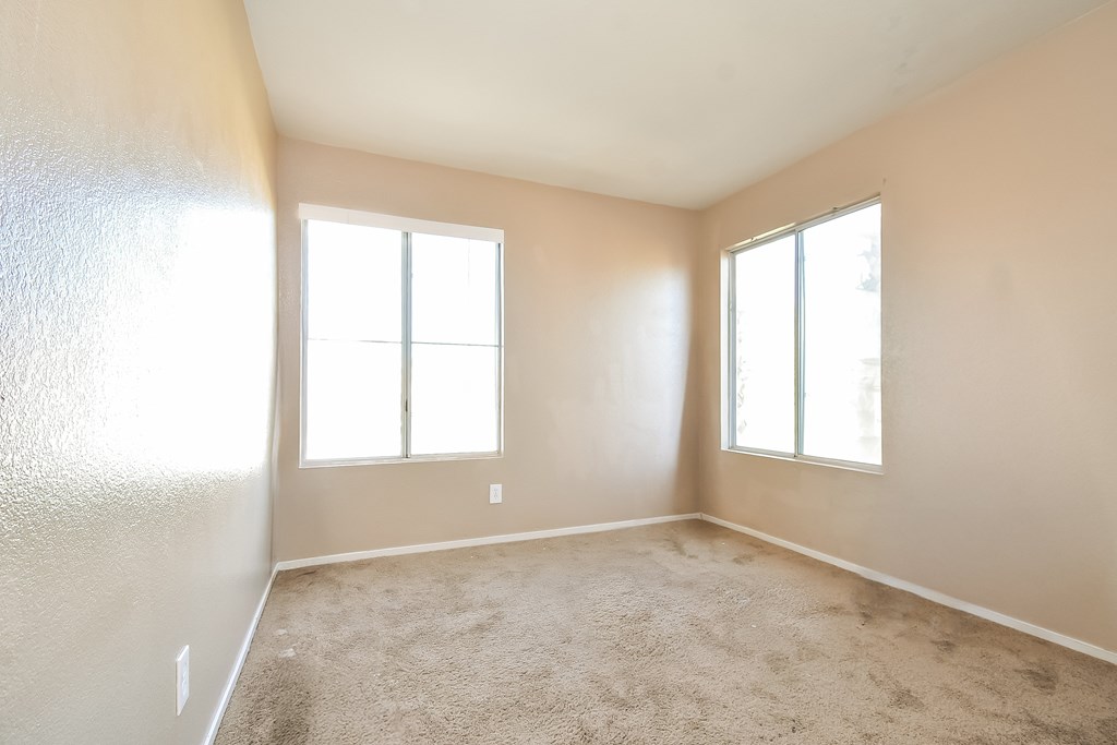 A room with two windows and carpeted floor.
