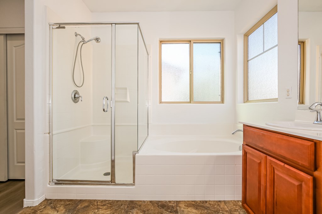 A bathroom with a glass shower stall and a bathtub.