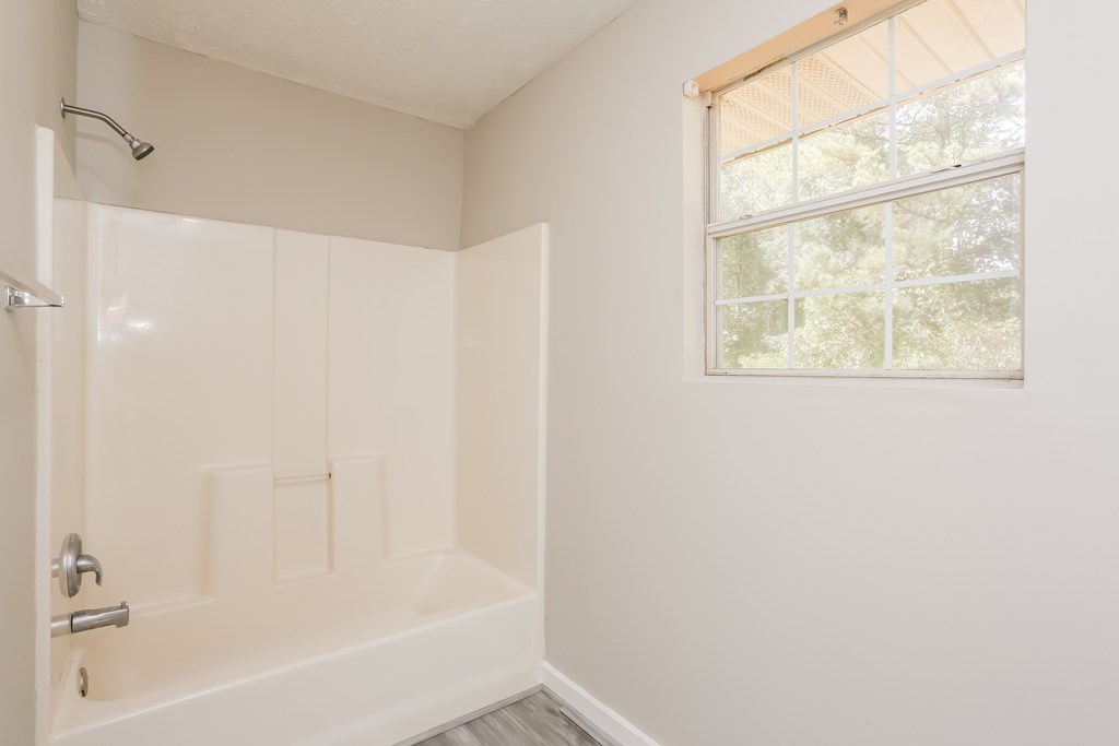 A white bathroom with a window and a shower.