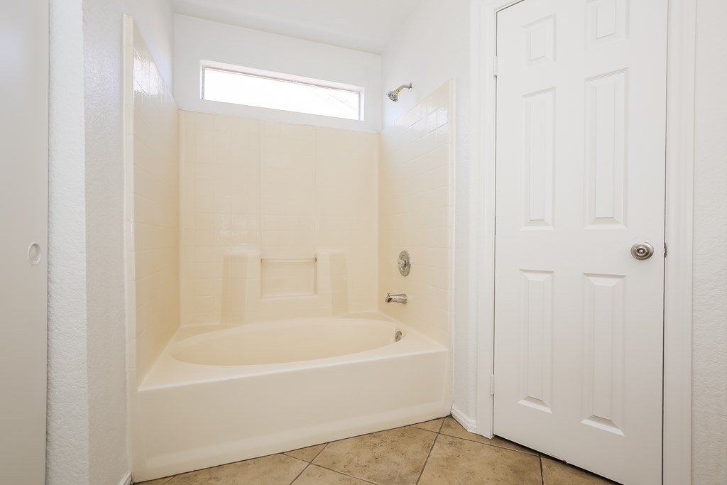 A white bathroom with a bathtub and a door.