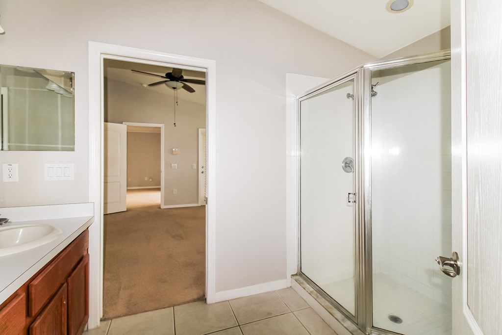 A bathroom with a walk-in shower and a fan.