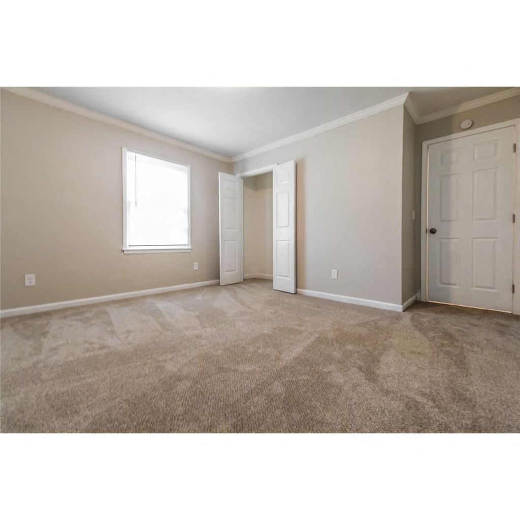 an empty living room with a door and a closet
