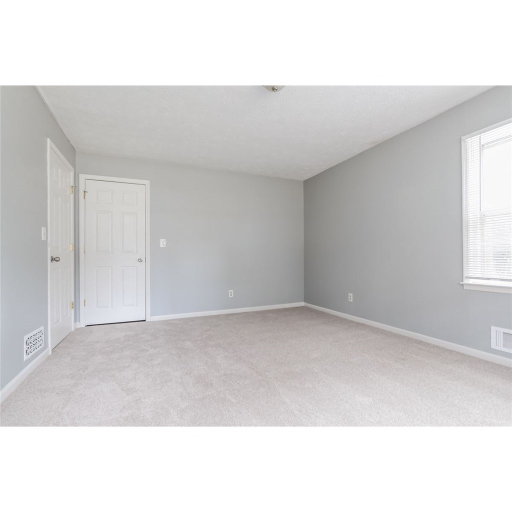 an empty bedroom with a door and a window