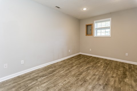 A room with a window and wooden flooring.