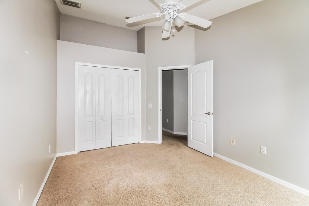 A room with a ceiling fan and two doors.