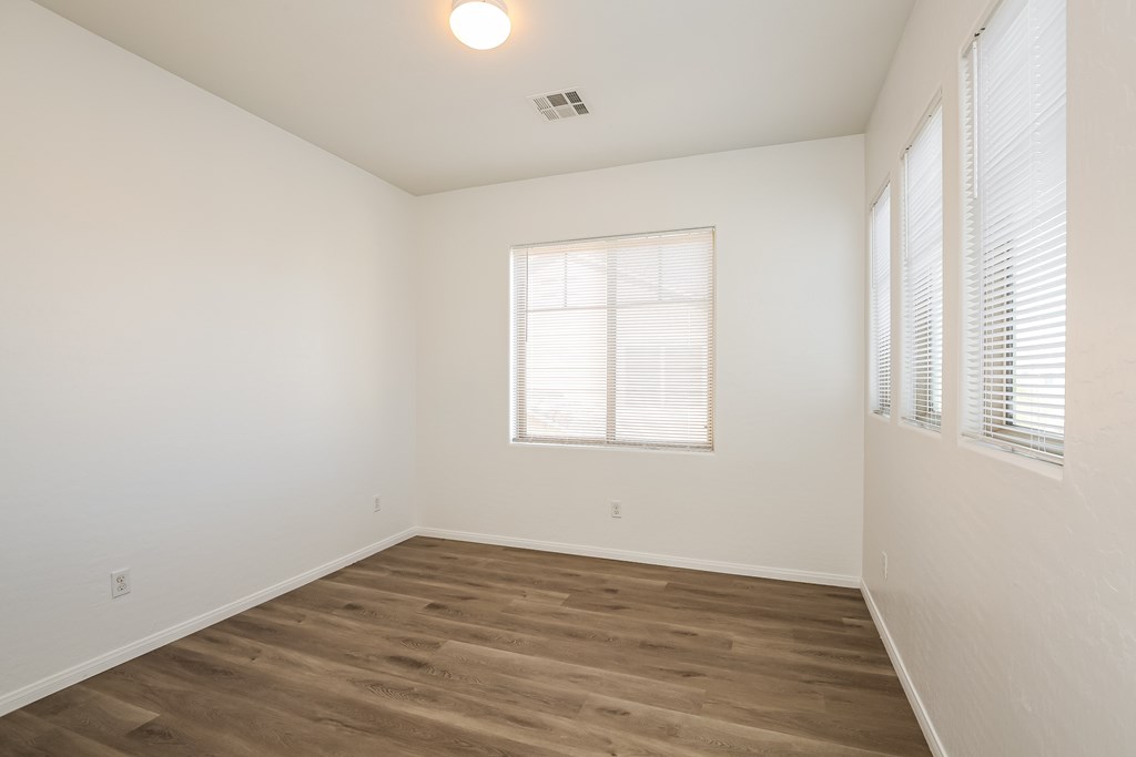 A room with wooden flooring and a window with blinds.