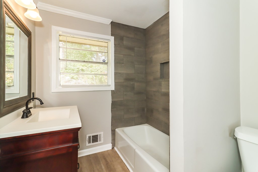 A bathroom with a white tub and a window.