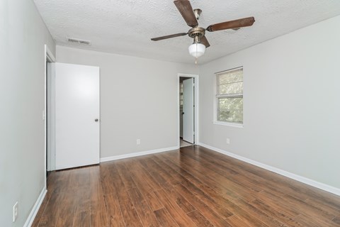 A room with a ceiling fan and wooden flooring.