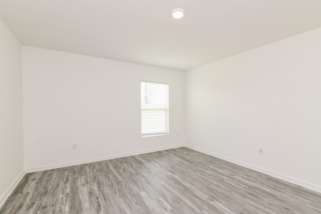 A room with a window and wooden flooring.