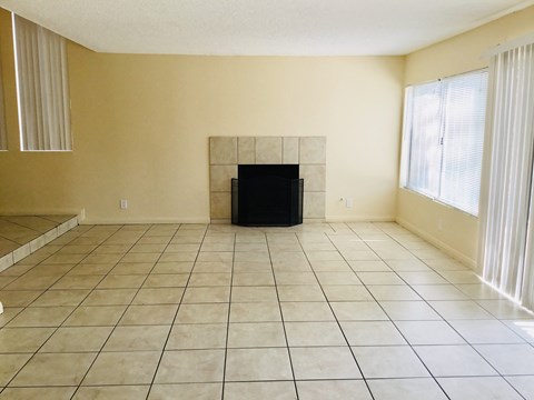 an empty living room with a tiled floor and a fireplace