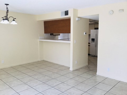 an empty living room with a kitchen and a tiled floor