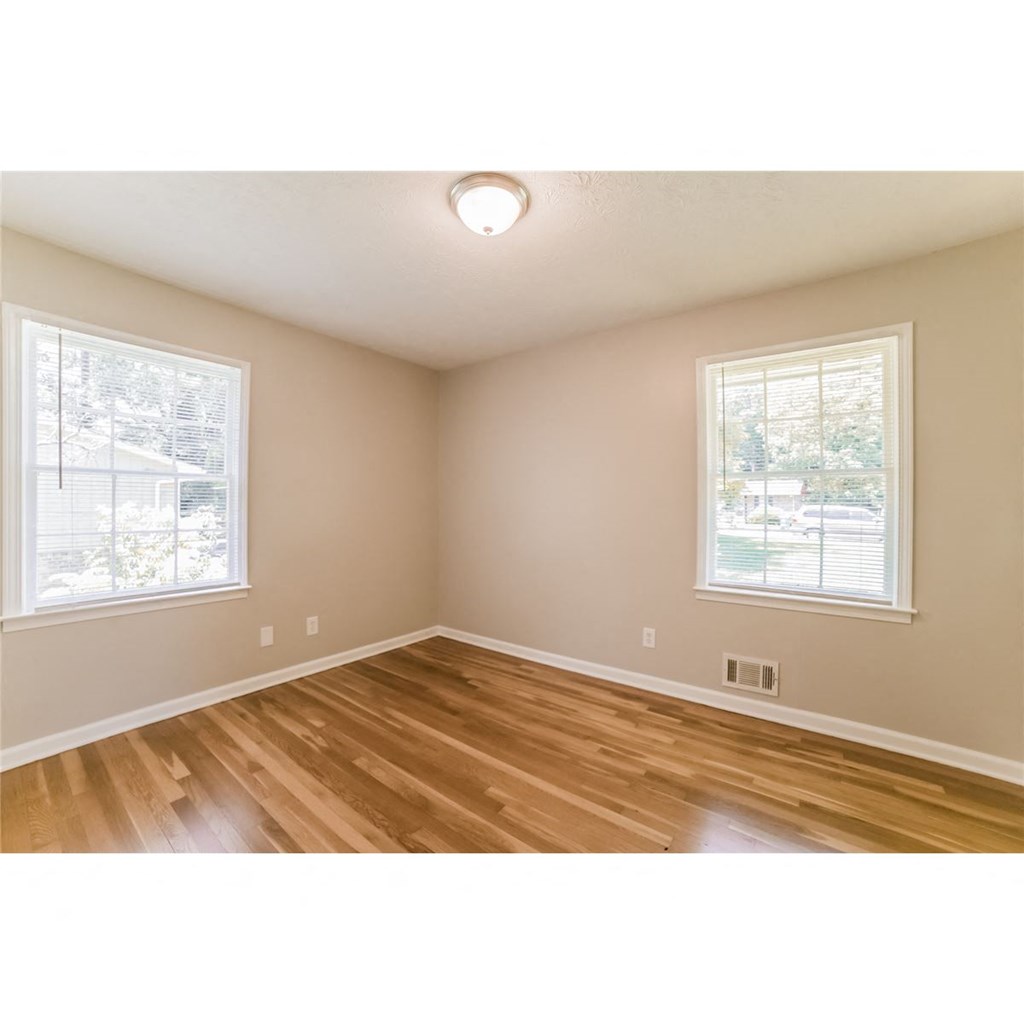 an empty living room with wood floors and two windows