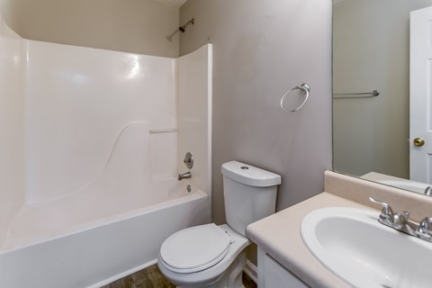 A white toilet sits next to a white bathtub in a small bathroom.