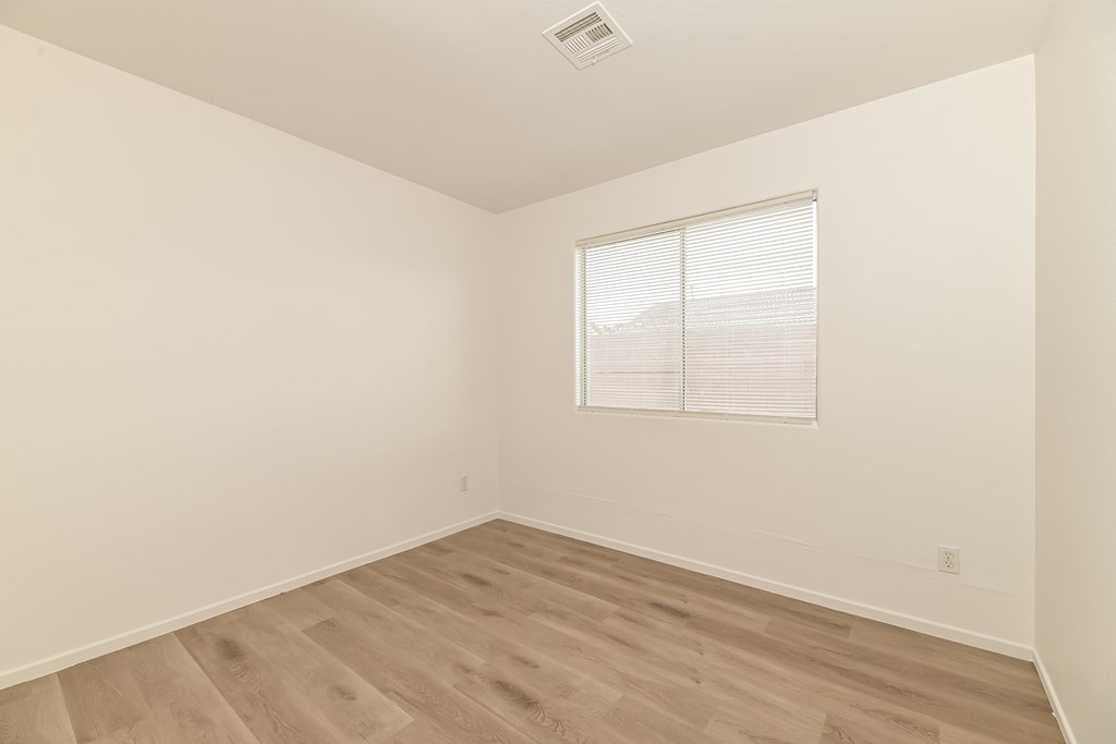 A room with a window and wooden flooring.