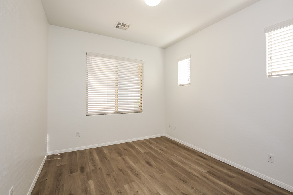 A room with wooden flooring and a window with blinds.