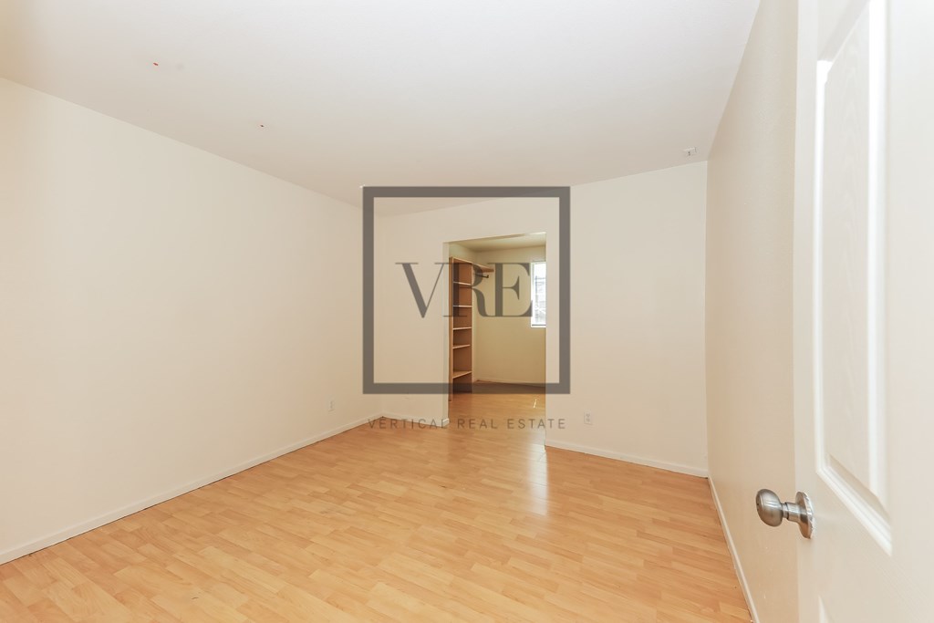 A room with a wooden floor and a door on the right side.