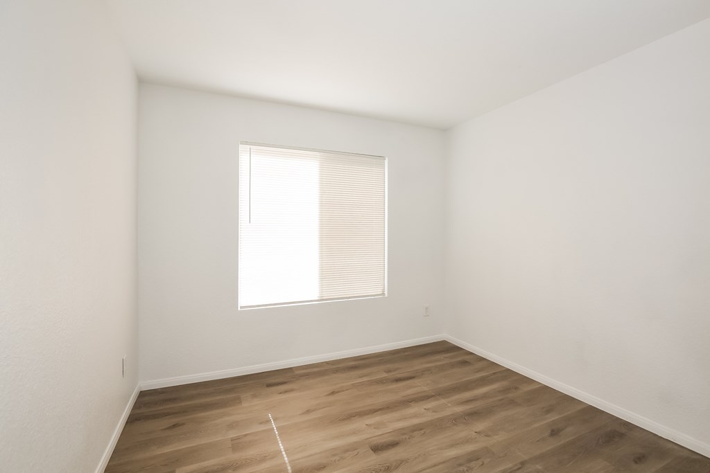 A room with a window and wooden flooring.
